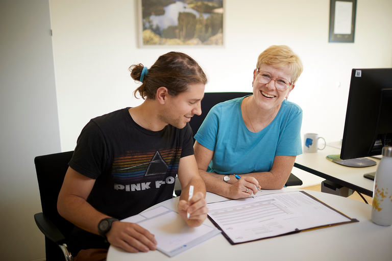 Zwei Kolleg*innen sitzen am Bürotisch